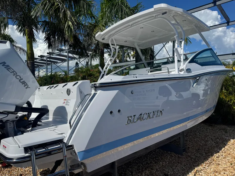 Slide: The Image of 2026 Blackfin 272 DC boat with Mercury engine, parked outdoors under palm trees. - 5