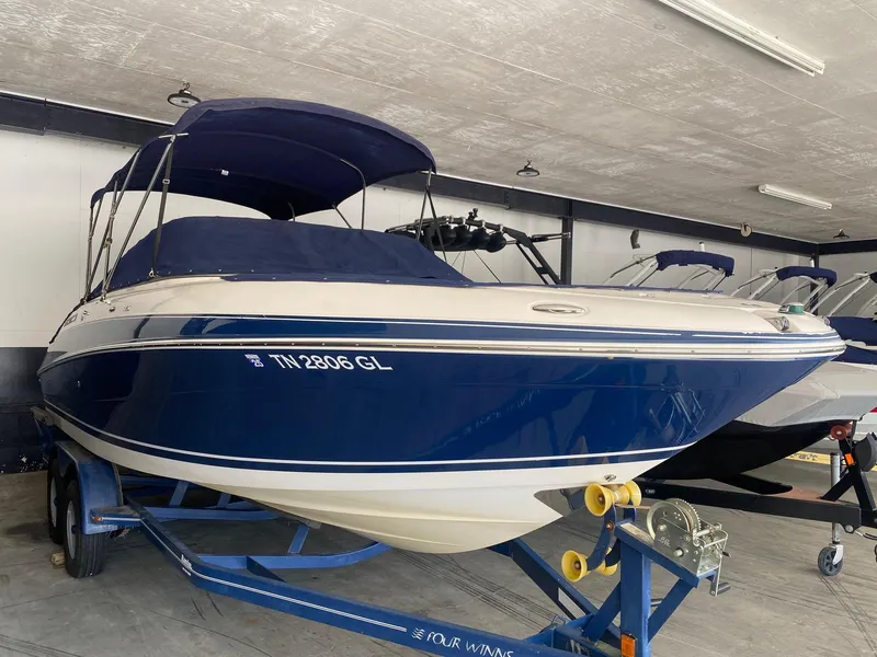 Slide: The Image of 2008 Four Winns H260 boat in storage, blue and white exterior, on a trailer. - 17