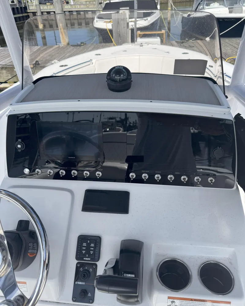 Slide: The Image of 2022 Sportsman Open 232 Center Console dashboard with controls and compass at marina. - 3
