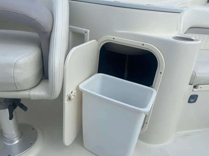 Slide: The Image of 2005 Stingray 250 LR boat interior with open storage compartment and trash bin. - 21