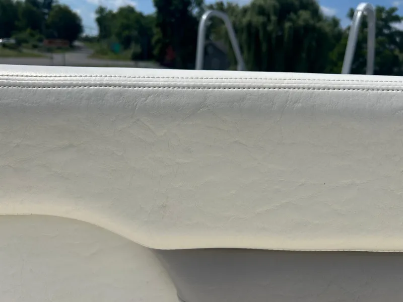 Slide: The Image of White leather upholstery on a 2005 Stingray 250 LR boat, with outdoor background. - 33