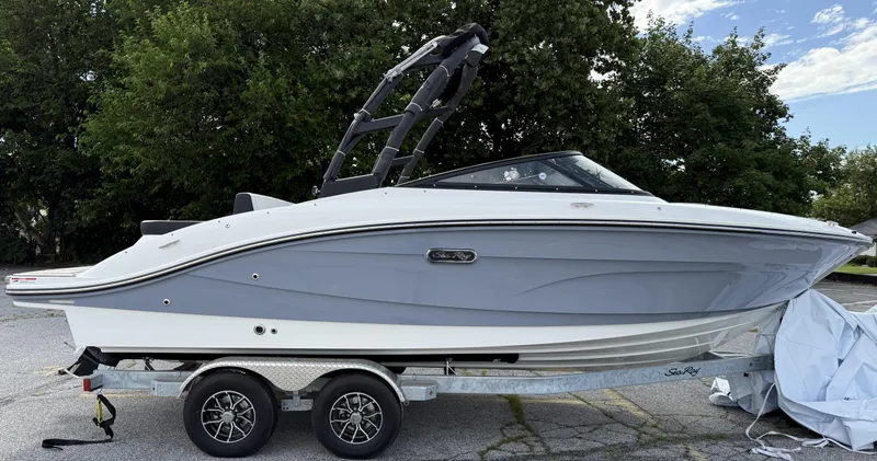 Slide: The Image of 2025 Sea Ray SPX 210 boat on trailer, parked outdoors with trees in background. - 2