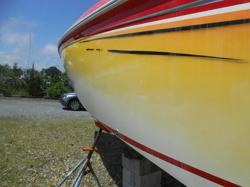 Slide: The Image of 2007 Sunsation 32 SS boat with vibrant red and yellow hull, parked on a trailer. - 17