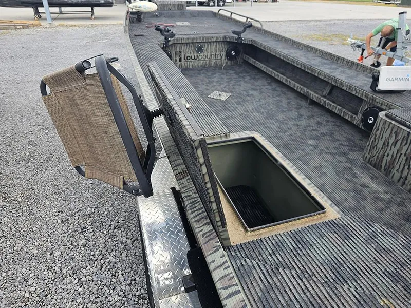 Slide: The Image of 2023 Low Country Swamp Fox 1854 boat interior with open storage compartment and foldable seat. - 9