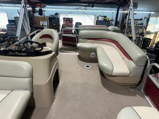 Slide: The Image of 2012 Sun Tracker Party Barge 20 DLX interior with beige and red seating in a garage. - 13