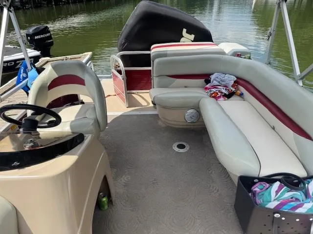 Slide: The Image of 2012 Sun Tracker Party Barge 20 DLX interior with seating and steering wheel on a calm lake. - 5