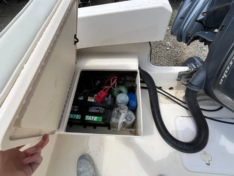 Slide: The Image of Open storage compartment on a 2005 Parker 2100 Special Edition boat, revealing battery and supplies. - 29