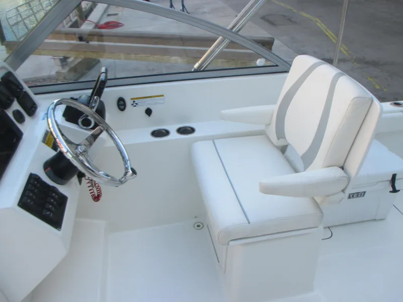 Slide: The Image of 2013 Carolina Cat 230 DC boat cockpit with steering wheel and white seating. - 16