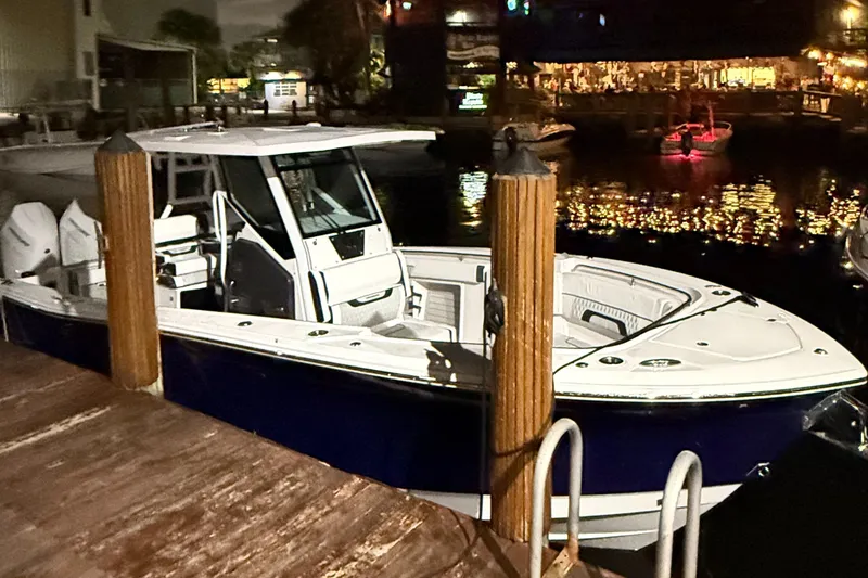 The Image of 2025 Blackfin 302 CC boat docked at night, reflecting lights on water. - 1