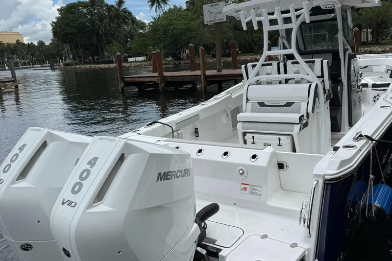 Slide: The Image of 2025 Blackfin 302 CC boat with dual Mercury 400 engines docked by a scenic waterfront. - 4