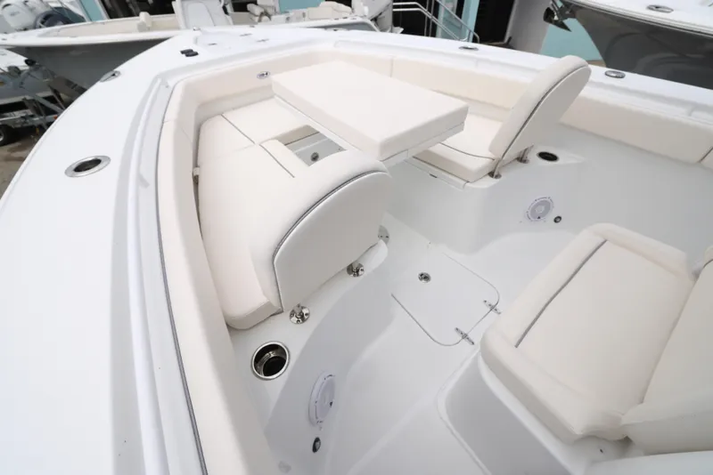 Slide: The Image of 2025 Sea Hunt Gamefish 27 Forward Seating boat interior with white cushioned seats and table. - 13