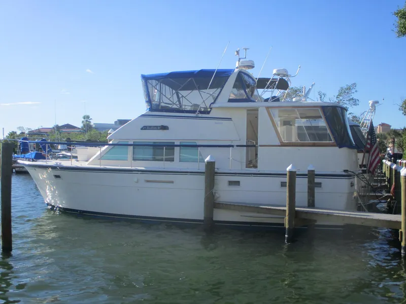 The Image of 1986 Hatteras 43 Double Cabin yacht docked in a marina under clear blue sky. - 1