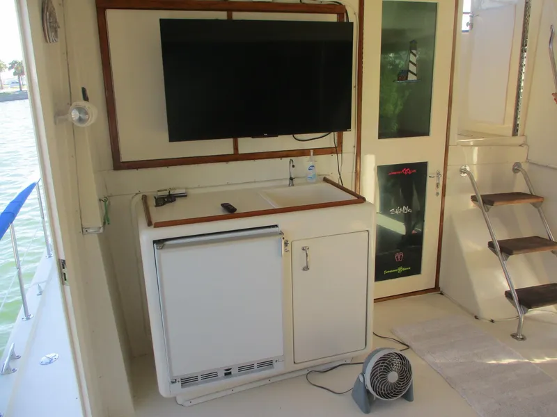 Slide: The Image of 1986 Hatteras 43 Double Cabin interior with TV, mini fridge, and stairs. - 12