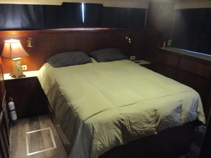 Slide: The Image of Cozy bedroom in 1986 Hatteras 43 Double Cabin yacht with wood paneling and soft lighting. - 23