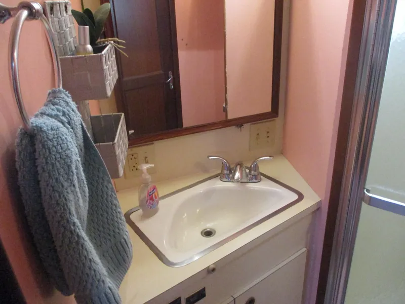 Slide: The Image of Bathroom sink area in 1986 Hatteras 43 Double Cabin yacht, featuring a mirror and towel. - 35