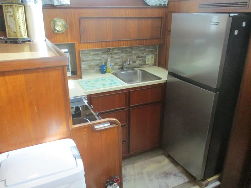 Slide: The Image of 1986 Hatteras 43 Double Cabin kitchen with wood cabinetry, stainless steel fridge, and compact sink. - 39