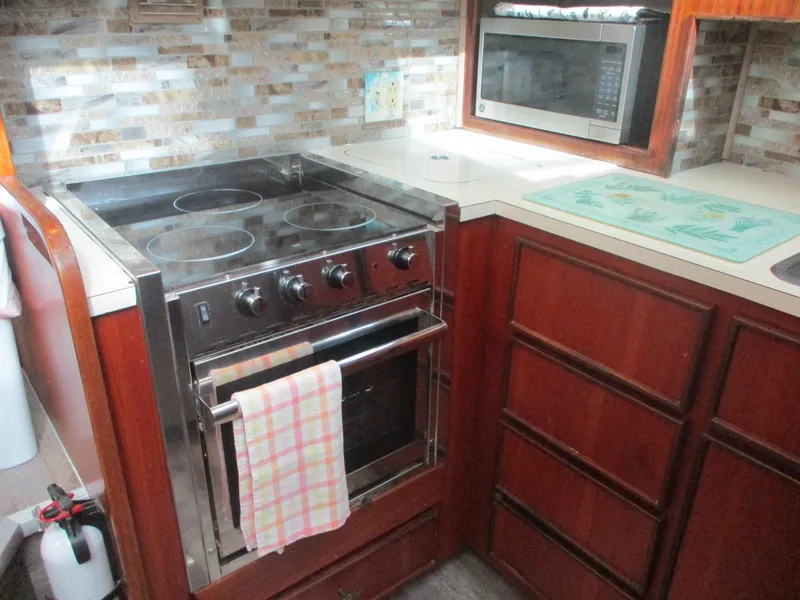 Slide: The Image of 1986 Hatteras 43 Double Cabin kitchen with stove, microwave, and wooden cabinetry. - 40