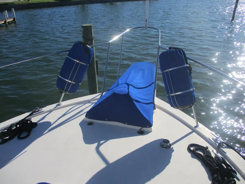 Slide: The Image of Bow of 1986 Hatteras 43 Double Cabin with blue fenders and cover on sunny water. - 7