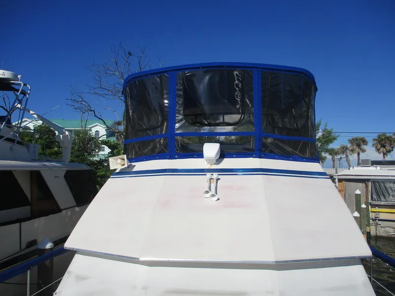 Slide: The Image of 1986 Hatteras 43 Double Cabin yacht with blue canopy, docked under clear sky. - 8