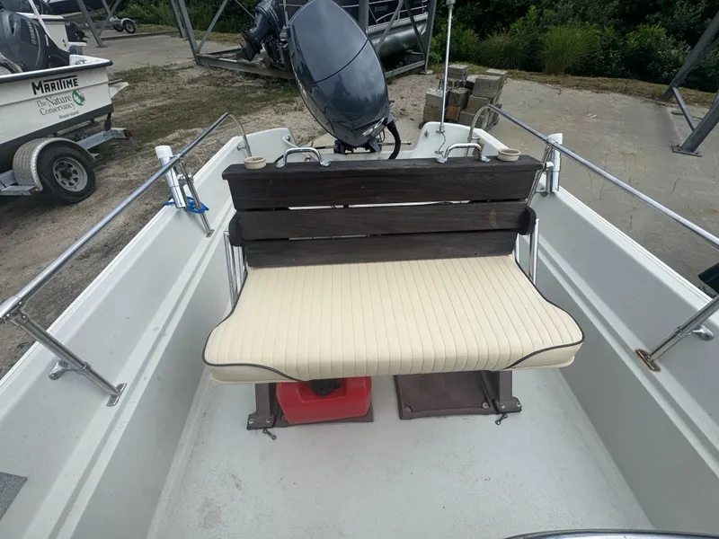 Slide: The Image of 1984 Boston Whaler 170 Montauk boat interior with cushioned bench seat and outboard motor. - 13