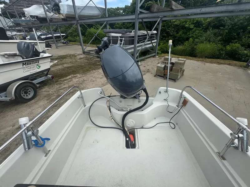 Slide: The Image of 1984 Boston Whaler 170 Montauk boat interior with motor, parked outdoors. - 14