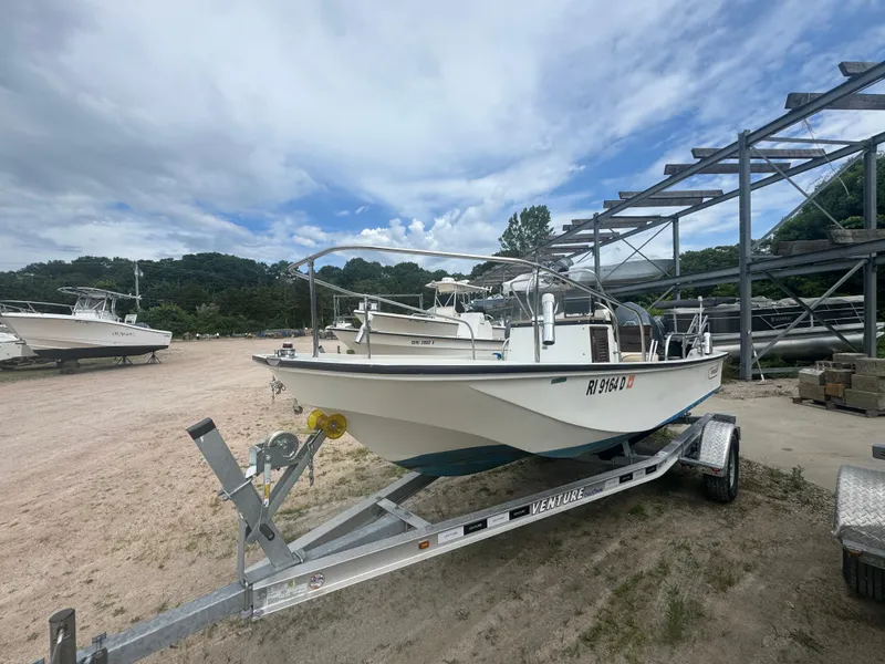 Slide: The Image of 1984 Boston Whaler 170 Montauk boat on trailer, parked outdoors under cloudy sky. - 17