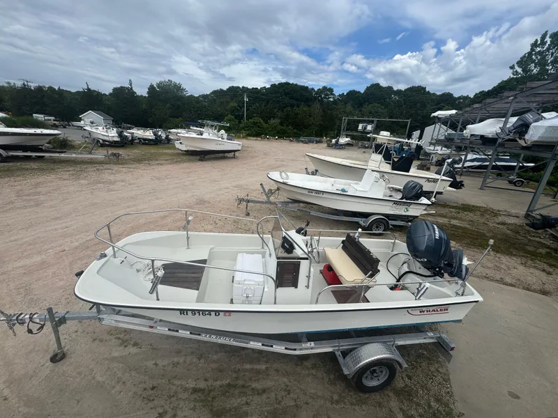 Slide: The Image of 1984 Boston Whaler 170 Montauk boat on trailer in a boatyard under cloudy sky. - 19