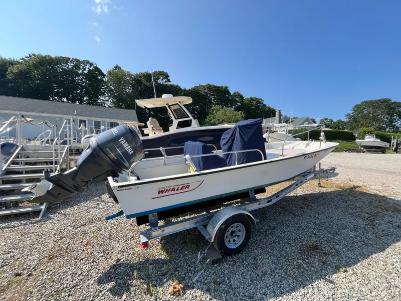 Slide: The Image of 1984 Boston Whaler 170 Montauk boat on trailer with Yamaha outboard motor, parked outdoors. - 24
