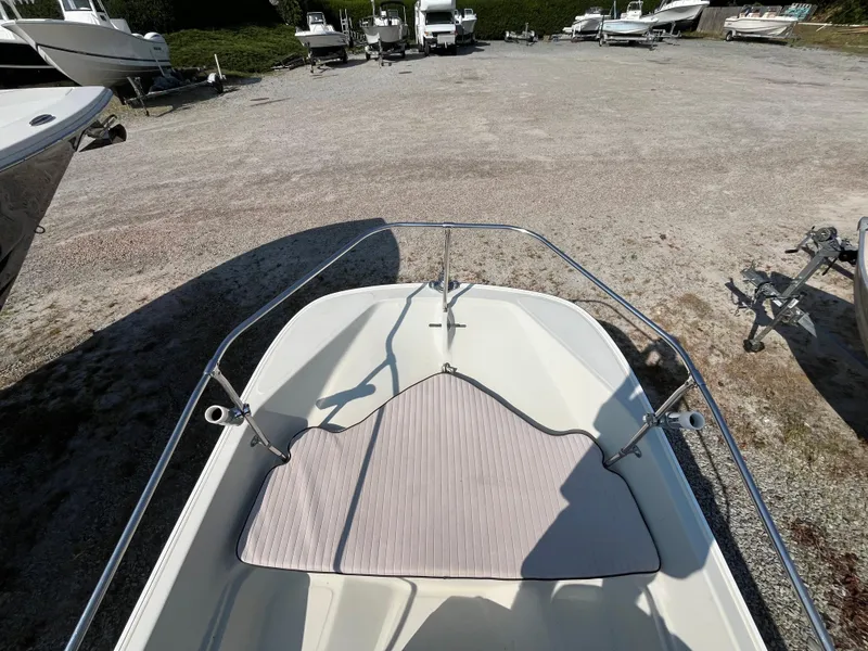 Slide: The Image of 1984 Boston Whaler 170 Montauk boat on gravel lot, surrounded by other boats. - 27
