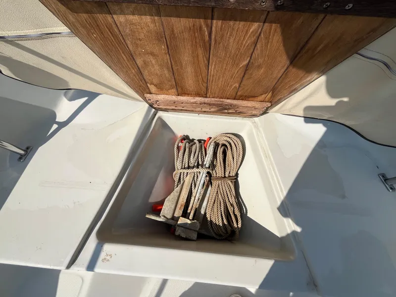 Slide: The Image of 1984 Boston Whaler 170 Montauk boat storage compartment with coiled rope and anchor. - 30