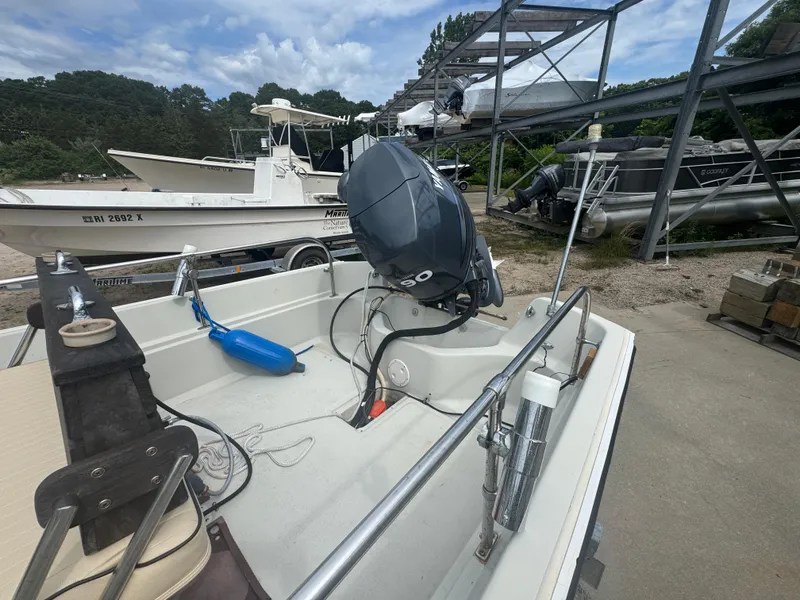 Slide: The Image of 1984 Boston Whaler 170 Montauk boat with outboard motor in a marina setting. - 6