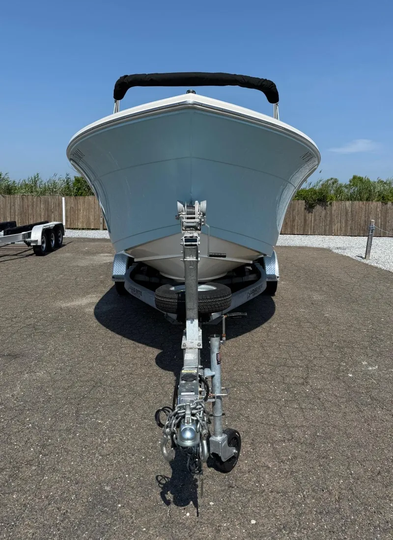 Slide: The Image of 2017 Cobia 220 Dual Console boat on trailer, parked outdoors under clear blue sky. - 7