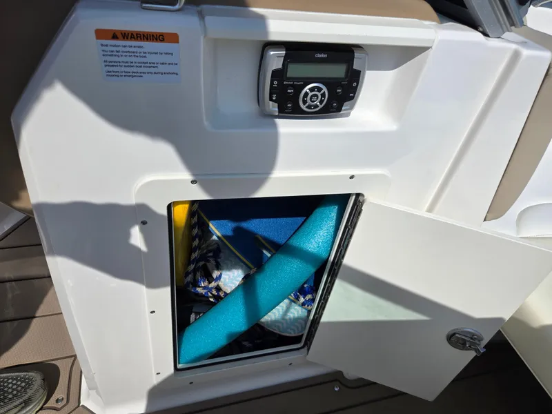 Slide: The Image of 2022 Chaparral 21 SSi boat storage compartment with open door and visible contents. - 14