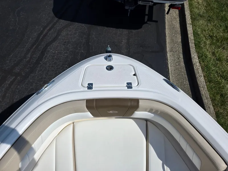 Slide: The Image of 2022 Chaparral 21 SSi boat bow with white and beige seating, parked on pavement. - 19