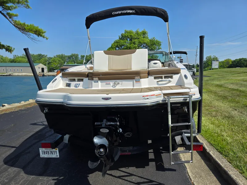 Slide: The Image of 2022 Chaparral 21 SSi boat with swim platform and ladder, parked near water. - 2