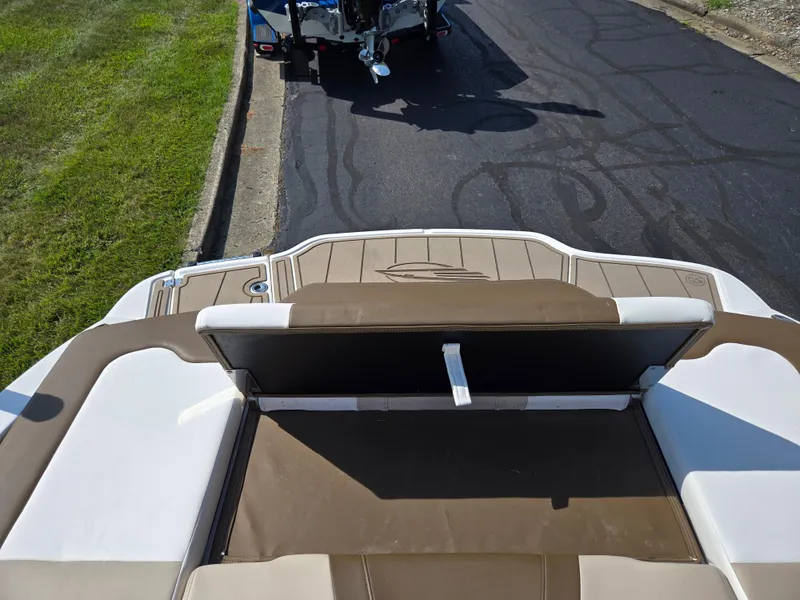 Slide: The Image of 2022 Chaparral 21 SSi boat interior with brown and white seating, parked on pavement. - 24