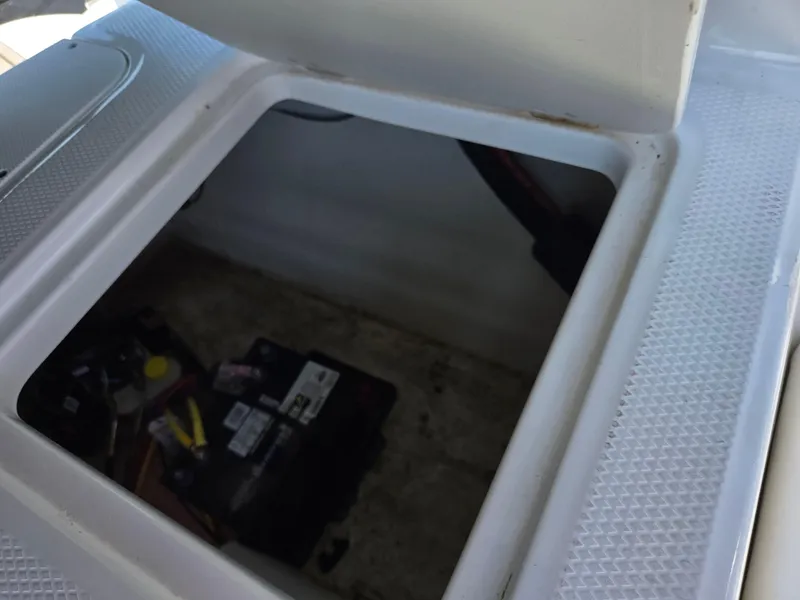 Slide: The Image of Open storage compartment in 2022 Chaparral 21 SSi boat, revealing battery and tools. - 26