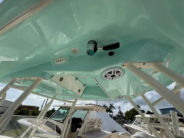 Slide: The Image of 2015 Cobia 296 Center Console boat with teal hardtop and mounted speakers. - 18
