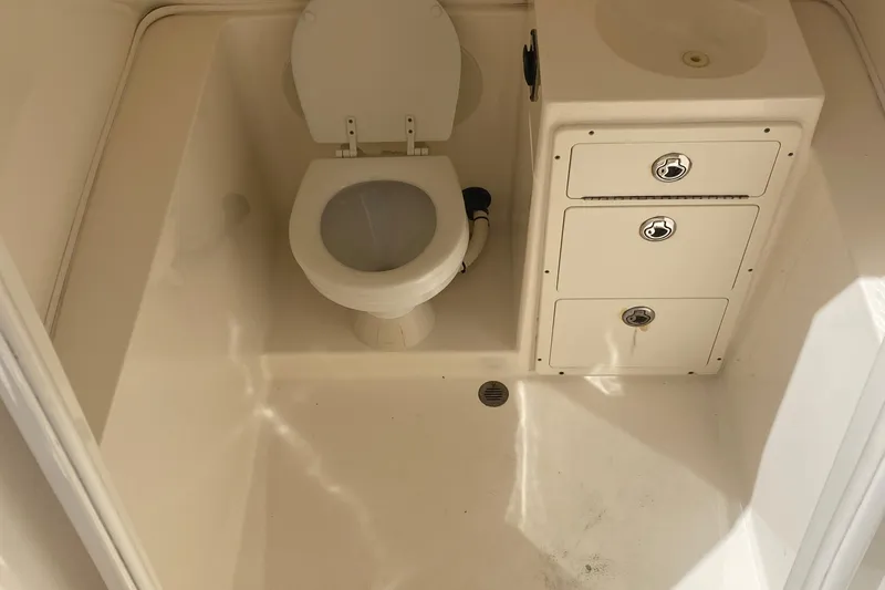 Slide: The Image of 2015 Cobia 296 Center Console boat bathroom with toilet and storage compartments. - 33
