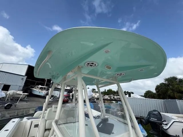 Slide: The Image of 2015 Cobia 296 Center Console boat with teal canopy, docked under a clear blue sky. - 36