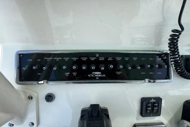 Slide: The Image of Control panel of a 2015 Cobia 296 Center Console boat with various switches and controls. - 41