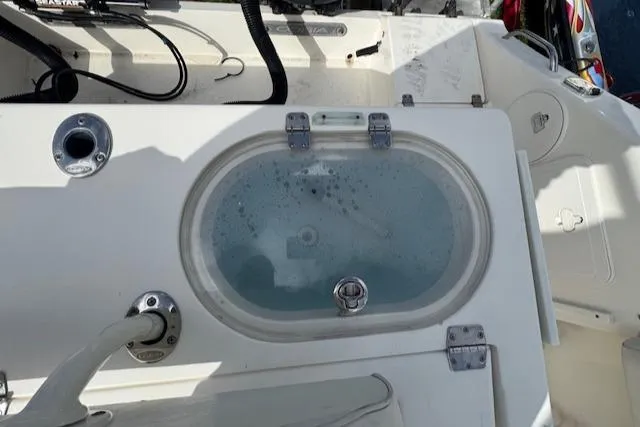 Slide: The Image of 2015 Cobia 296 Center Console livewell with water, featuring secure latches and plumbing. - 45