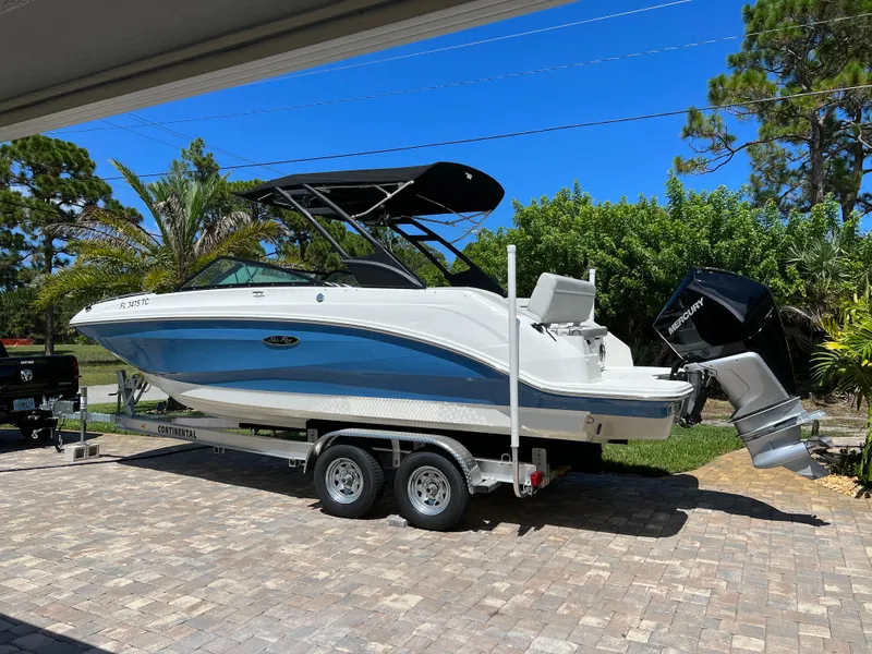 The Image of 2022 Sea Ray 250 SDX-OB boat on trailer, parked outdoors under clear blue sky. - 0
