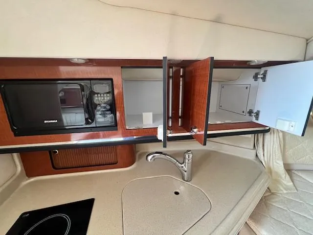 Slide: The Image of 2003 Sea Ray 290 Amberjack interior kitchen with microwave, sink, and open cabinets. - 13