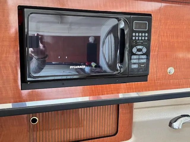 Slide: The Image of Microwave in 2003 Sea Ray 290 Amberjack boat interior, featuring wood paneling. - 15
