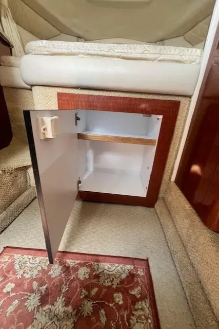 Slide: The Image of Open cabinet inside 2003 Sea Ray 290 Amberjack boat, featuring carpeted interior and floral rug. - 19