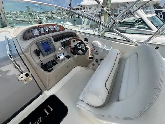 Slide: The Image of 2003 Sea Ray 290 Amberjack helm with gauges, steering wheel, and white seating. - 2