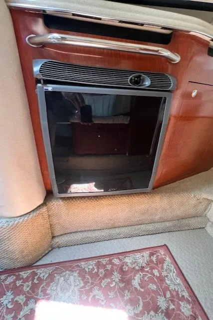 Slide: The Image of 2003 Sea Ray 290 Amberjack cabin interior with compact refrigerator and carpeted flooring. - 21