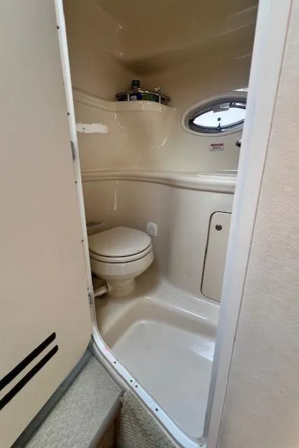 Slide: The Image of 2003 Sea Ray 290 Amberjack boat bathroom with toilet and porthole window. - 22