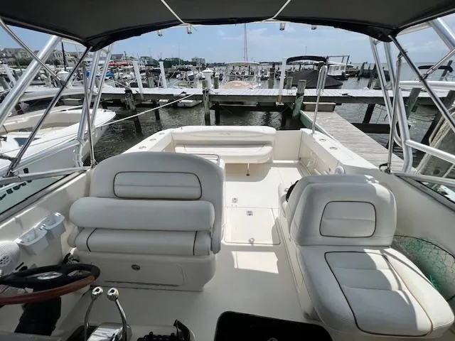 Slide: The Image of 2003 Sea Ray 290 Amberjack boat interior with white seating at a marina. - 6